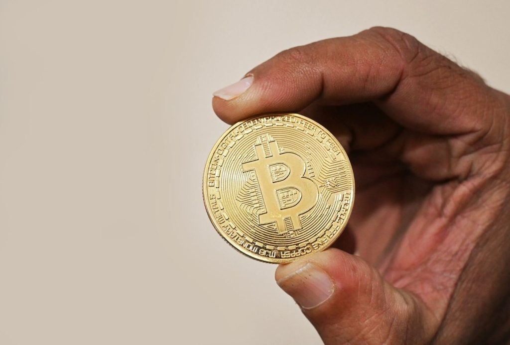 Investors Turn to AI Tools to Track Crypto Swings Bitcoin tokens in front of a trading chart on a screen