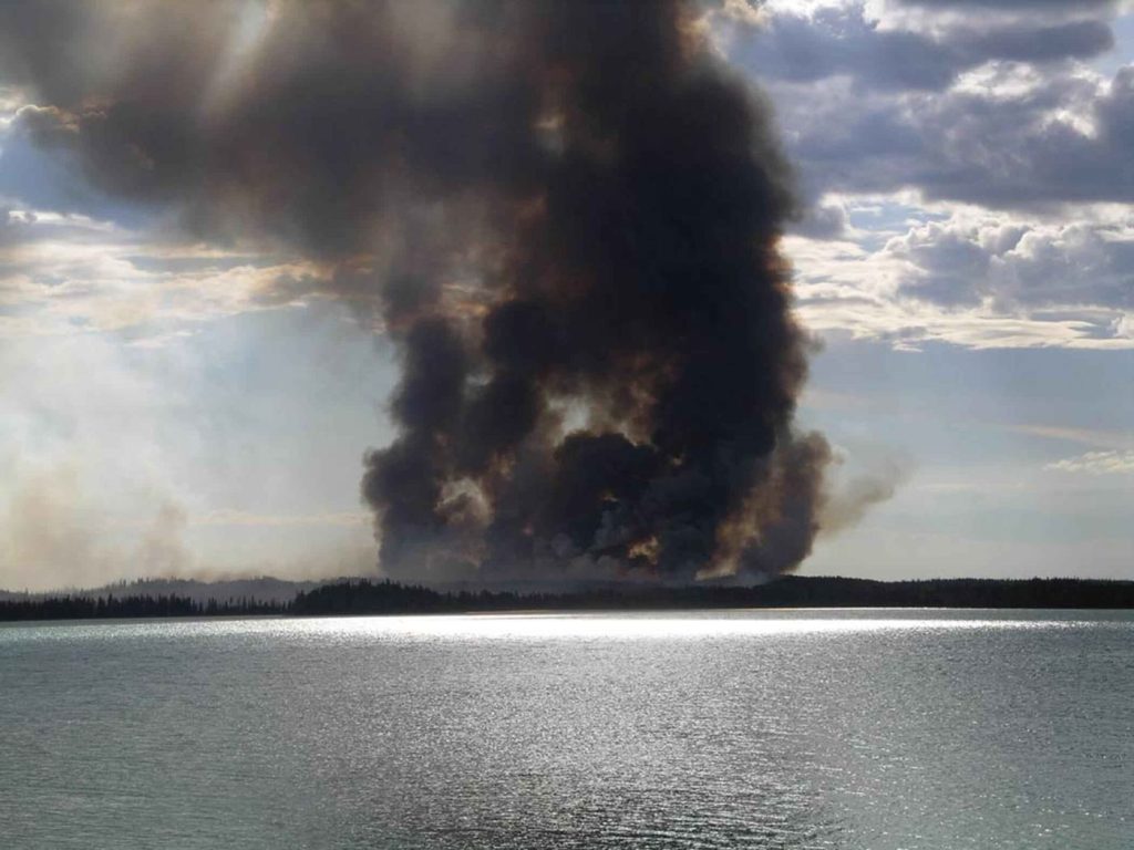 Smoke rising from a forest wildfire as crews work below